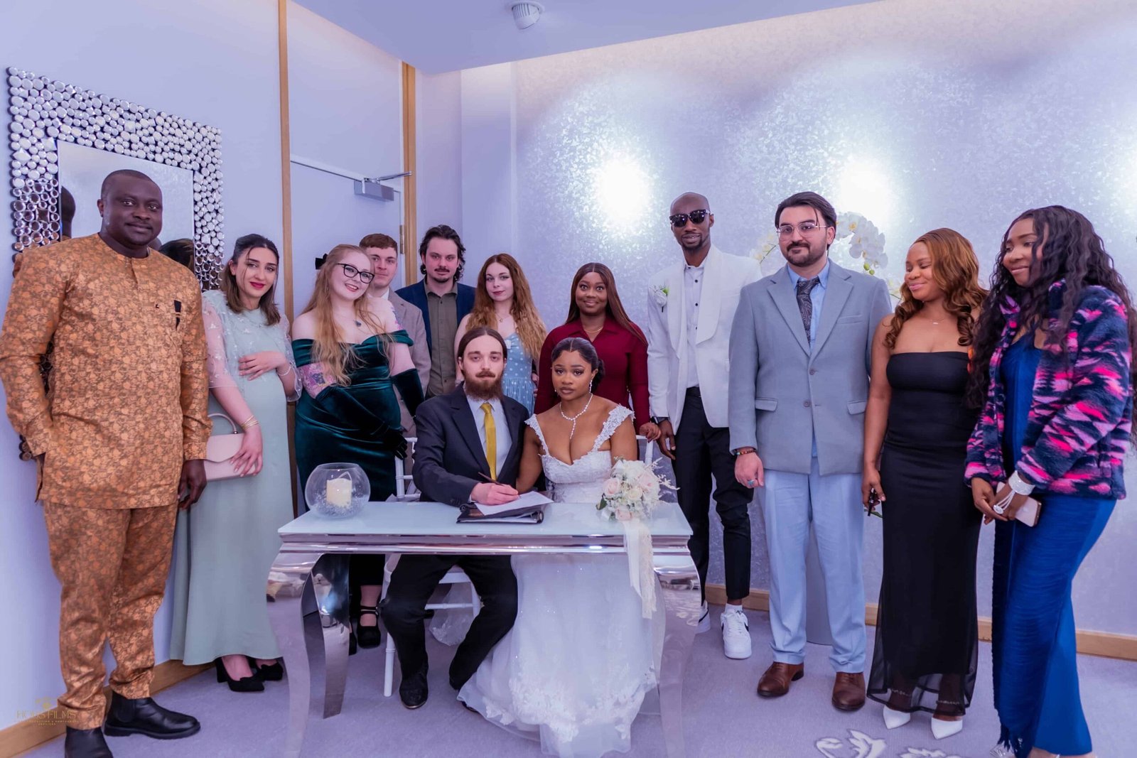Wedding party posing for a group photo around the signing table