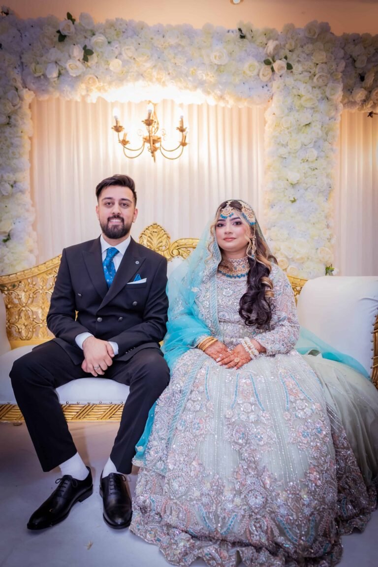 Bride and groom seated together on a floral wedding stage