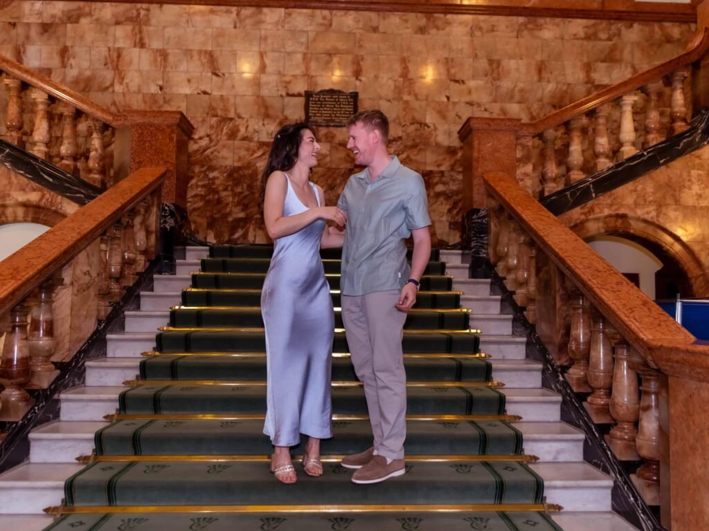 Bride in a blue satin gown and groom on a grand manor staircase – natural wedding photography in Wedding Photographer Colchester