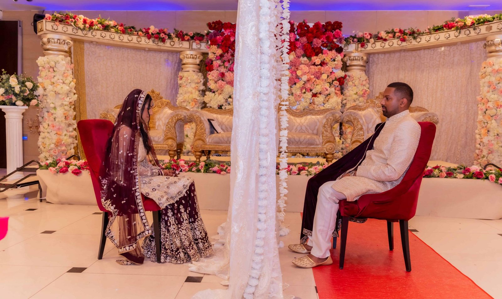 Couple on a gold stage sofa before a lavish pink floral backdrop, Colchester