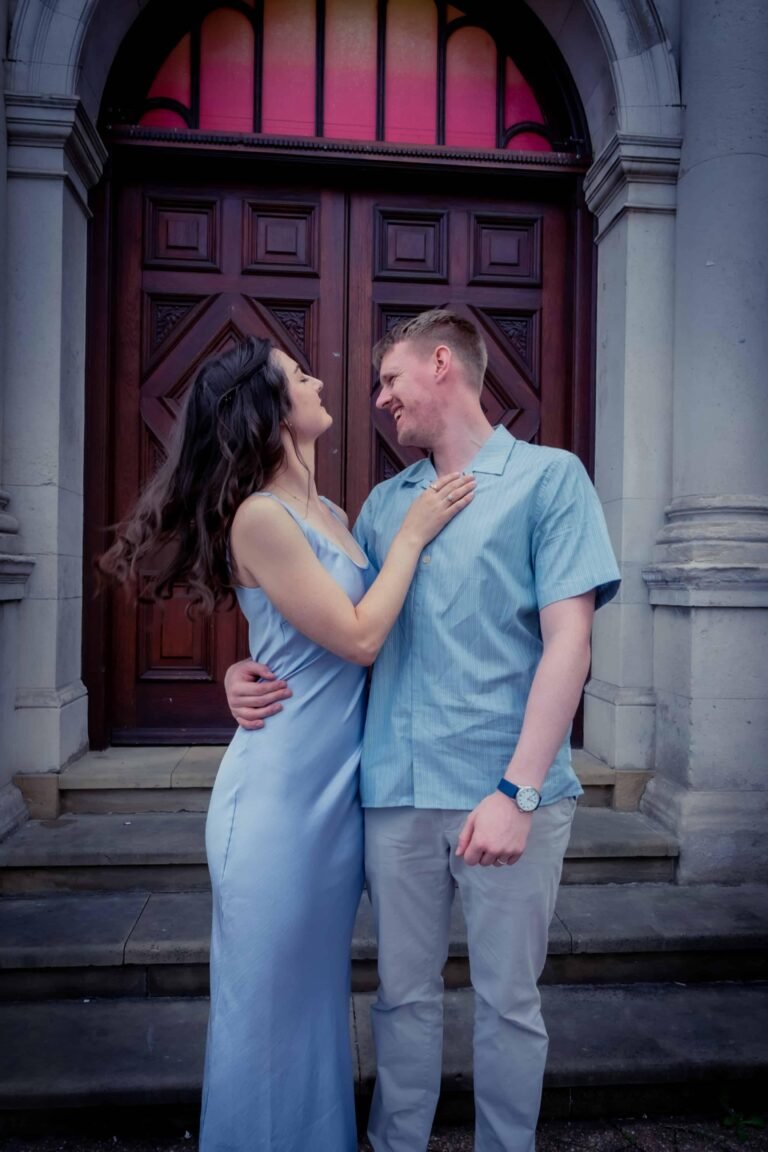 Bride in blue and groom in a tender pose at a grand arched wooden doorway
