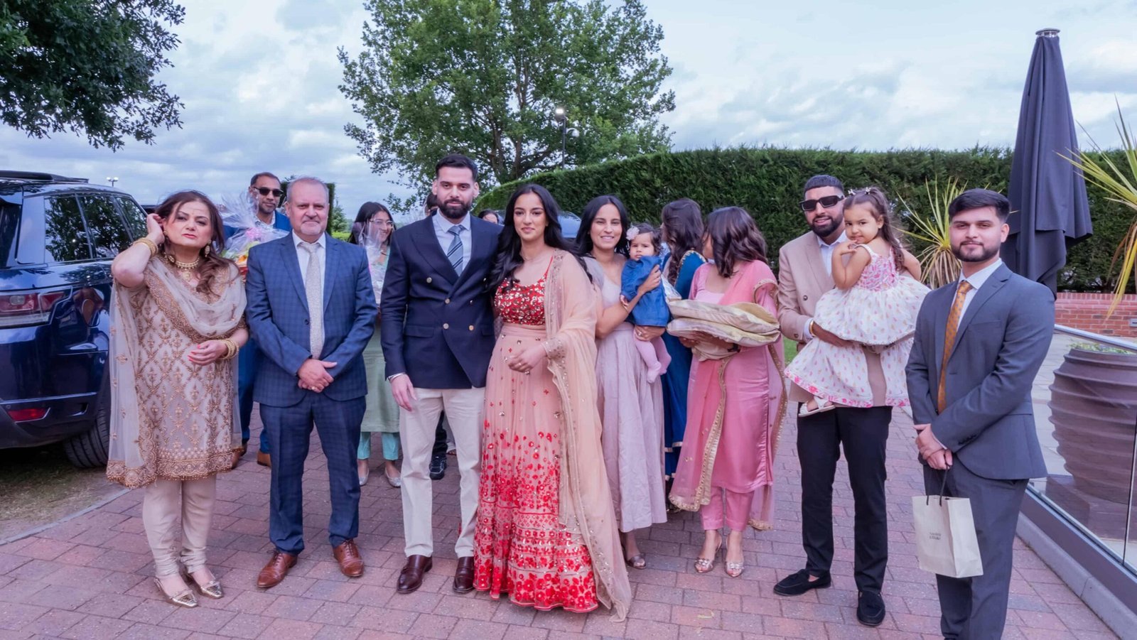 Wedding guests in colourful South Asian outfits gathered outdoors for a group photo
