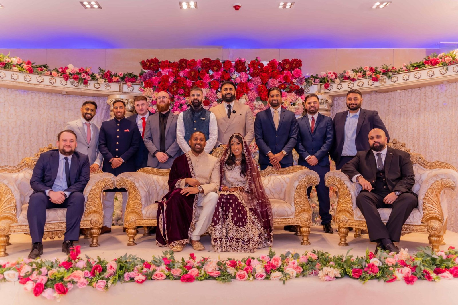 Guests seated with the couple on a floral-backed reception stage