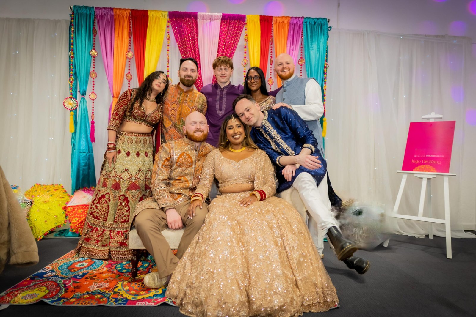 Family and friends in South Asian outfits gathered at a colourful mehndi celebration