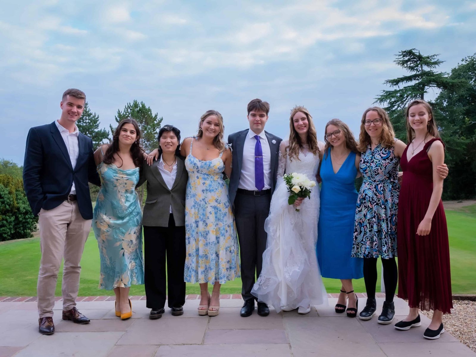 Wedding party gathered on a lawn for a group photo