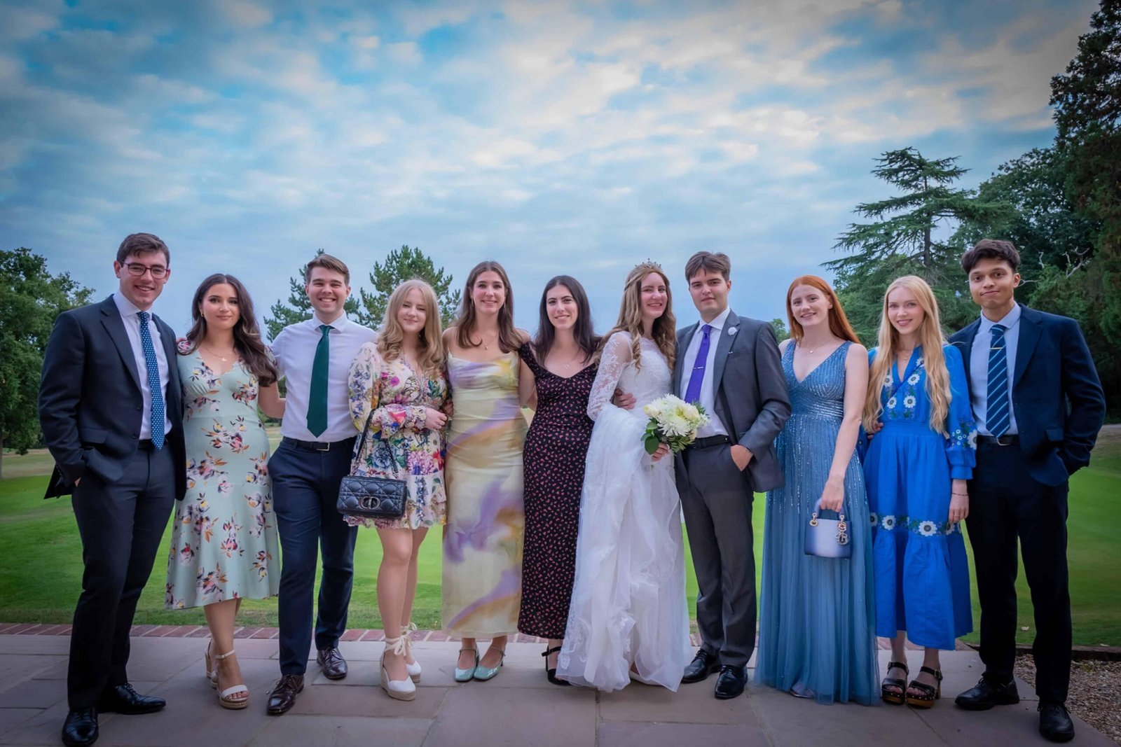 Large group of wedding guests in formal and colourful attire outdoors