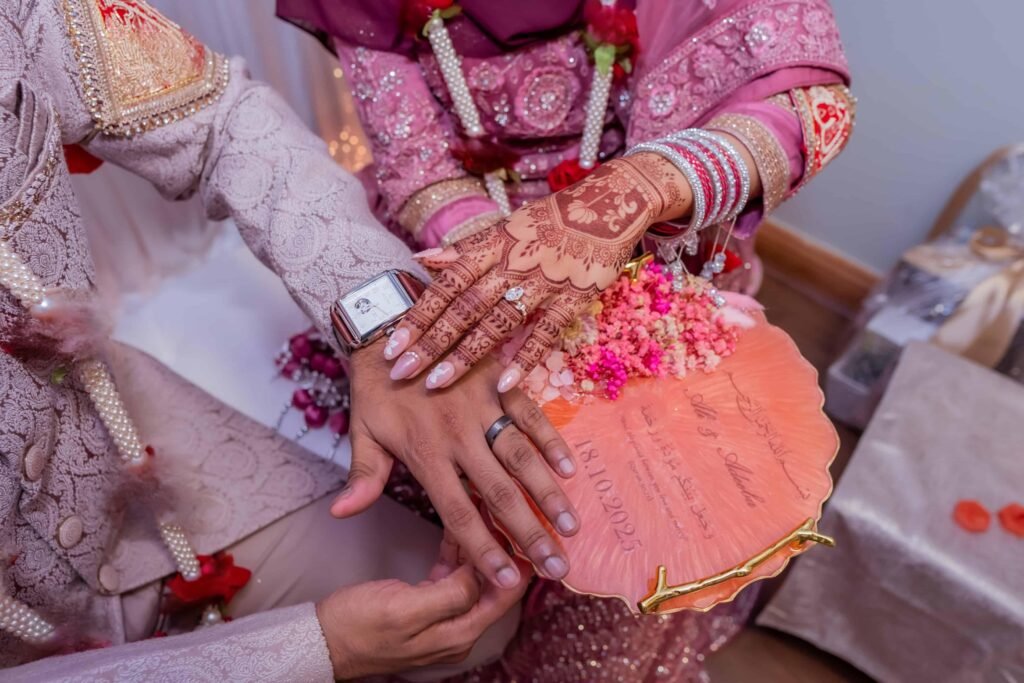 Close-up of the bride's henna hands and bangles resting with the groom's hands and rings