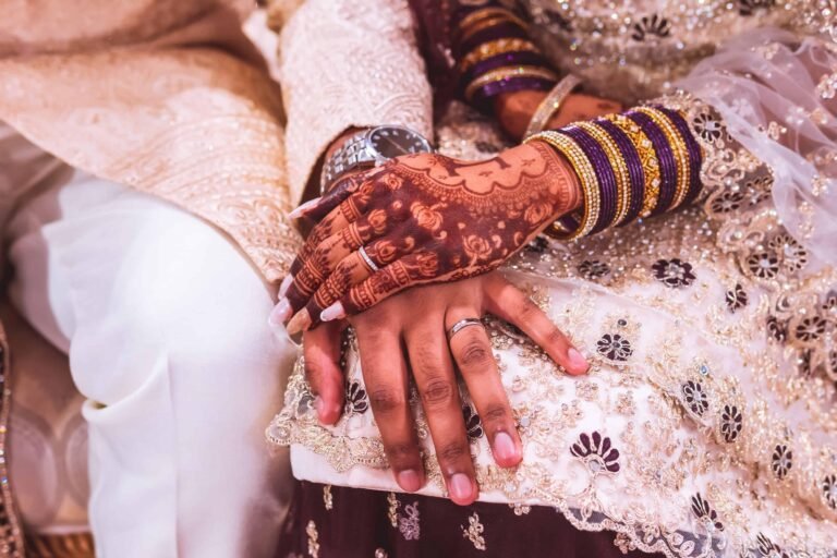 Close-up of the bride's henna-decorated hands and gold bangles with the wedding rings