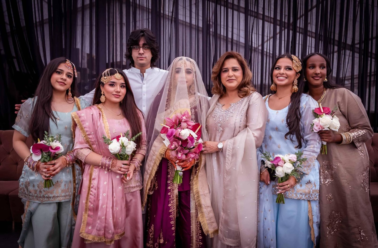 Bride with family and guests in traditional Asian wedding attire holding bouquets