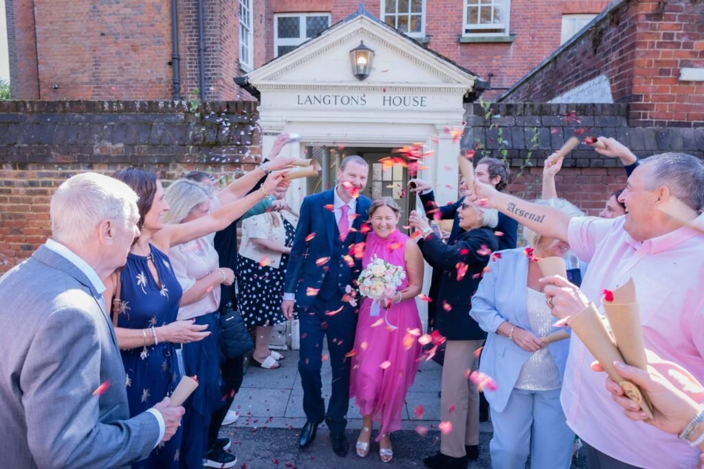 Wedding couple leaving Langtons House in London as guests shower them with colourful confetti after their wedding ceremony.