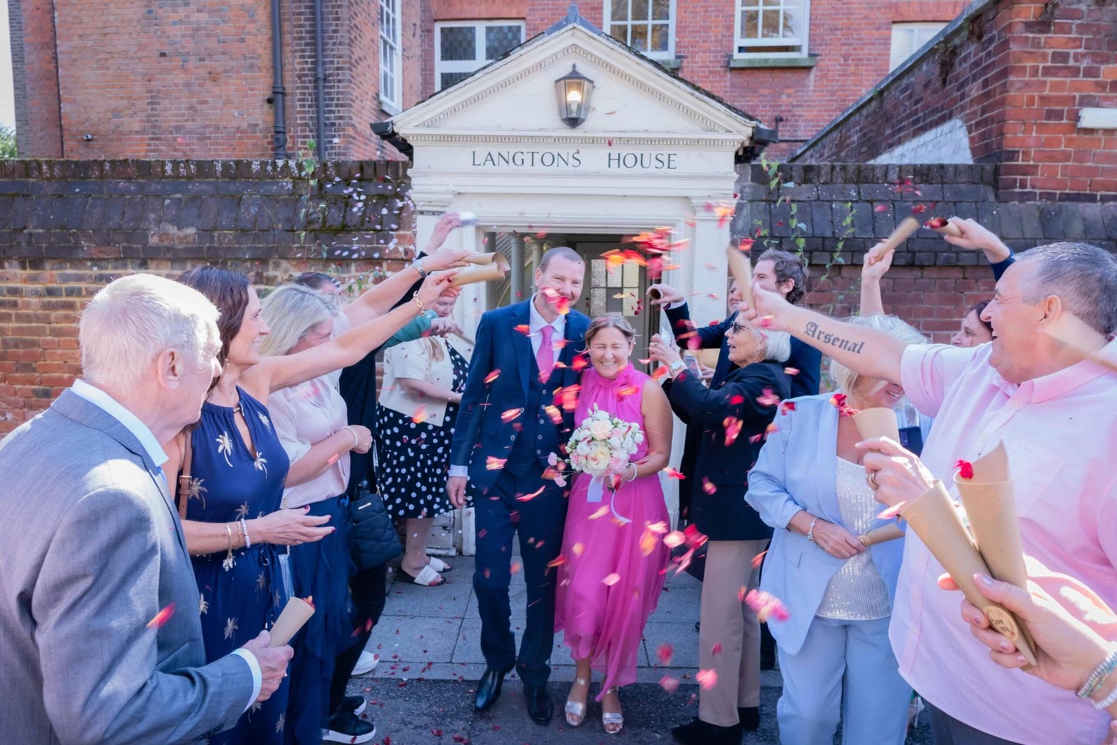 Wedding couple leaving Langtons House in London as guests shower them with colourful confetti after their wedding ceremony.